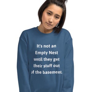 May include: A blue sweatshirt with white text that reads "It's not an Empty Nest until they get their stuff out of the basement."