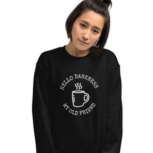Könnte beinhalten: Schwarzer Pullover mit einem weißen Grafikdesign, auf dem "Hello Darkness My Old Friend" mit einer dampfenden Kaffeetasse in der Mitte steht.