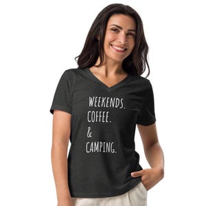 May include: A dark gray V-neck t-shirt with the words "WEEKENDS. COFFEE. & CAMPING." printed in white. The shirt is made of a soft material and is suitable for casual wear.