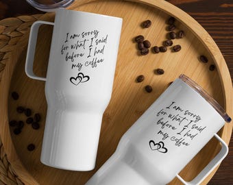 May include: Two white travel mugs with black text and hearts. The text on the mugs reads "I am sorry for what I said before I had my coffee".