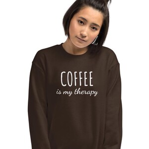 Könnte beinhalten: Ein braunes Sweatshirt mit dem Text "COFFEE is my therapy" in Weiß.