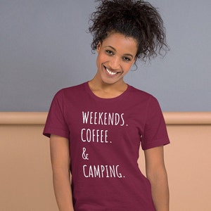 May include: A maroon t-shirt with white text that reads "Weekends. Coffee. & Camping."