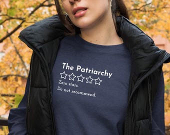 May include: A navy blue long-sleeved t-shirt with white text that reads "The Patriarchy" with a rating of zero stars and the text "Zero stars. Do not recommend."