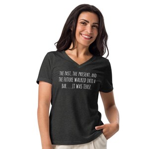 May include: A dark heather grey V-neck t-shirt with a white graphic print that reads "THE PAST, THE PRESENT, AND THE FUTURE WALKED INTO A BAR....IT WAS TENSE."