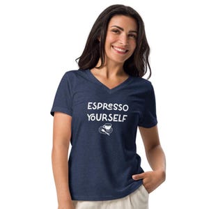 May include: A navy blue V-neck t-shirt featuring the white text "ESPRESSO YOURSELF" and a small coffee cup illustration. The shirt is made of a soft material. A casual top for coffee lovers.