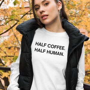 May include: White long-sleeved shirt with black text that reads "HALF COFFEE. HALF HUMAN."