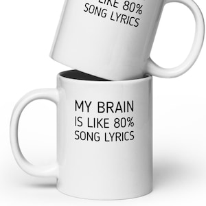 May include: White ceramic coffee mug with black text that reads "My brain is like 80% song lyrics".