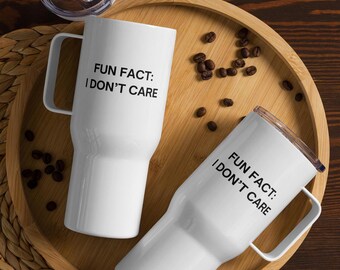 May include: Two white stainless steel travel mugs with black text that reads "Fun Fact: I Don't Care". The mugs are on a wooden tray with coffee beans scattered around them.
