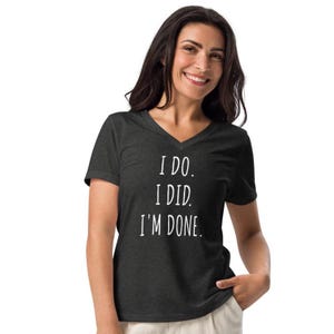 以下が含まれることがあります： 「I DO. I DID. I'M DONE.」の白文字がプリントされた、ダークグレーのVネックTシャツ。柔らかい素材でできており、ゆったりとしたフィット感です。カジュアルウェアアイテムです。