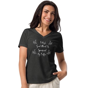 May include: Dark grey v-neck t-shirt featuring the white text "Today's Good Mood Is Sponsored By Coffee". The shirt has a relaxed fit and is made of a soft material. Coffee bean illustrations surround the text.