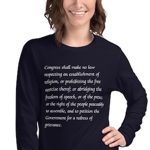 May include: Navy blue long-sleeve shirt with white text that reads "Congress shall make no law respecting an establishment of religion, or prohibiting the free exercise thereof; or abridging the freedom of speech, or of the press; or the right of the people peaceably to assemble, and to petition the Government for a redress of grievance."