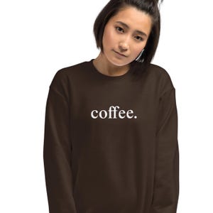 May include: A brown sweatshirt with the word "coffee." printed in white on the front.