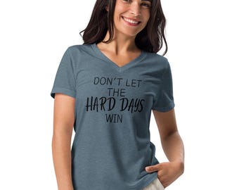 May include: A blue v-neck t-shirt with the text "Don't let the hard days win" printed in black.