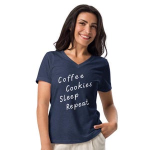 May include: A navy blue V-neck t-shirt with the words "Coffee Cookies Sleep Repeat" in white script. The shirt is made of a soft material and is suitable for casual wear.