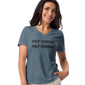 May include: A blue v-neck t-shirt with the text "HALF COFFEE. HALF HUMAN." printed in black.