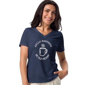 以下が含まれることがあります： 白いコーヒーカップと「Hello Darkness My Old Friend」というテキストが描かれた、ネイビーブルーのVネックTシャツです。