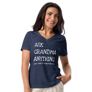 May include: A navy blue v-neck t-shirt with the text "ASK GRANDMA ANYTHING" in white, with the tagline "SHE'LL MAKE UP SOMETHING GOOD" below. The shirt is made of a soft material.