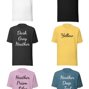 May include: Six different color t-shirts with various text printed on them. The colors are white, heather black, dark gray heather, yellow, heather prism lilac, and heather deep teal.