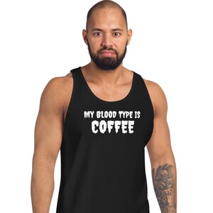 May include: Black vest top with the white text "MY BLOOD TYPE IS COFFEE". The text is in a bold, slightly distressed font. The top is sleeveless and made of a soft material.