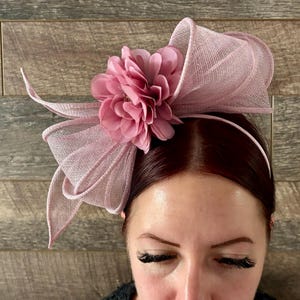 May include: A pink and white headband with a large pink flower. The headband is made of a soft, delicate material and is perfect for a special occasion.