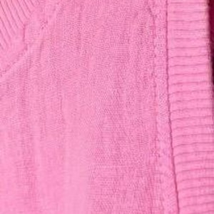 Pu&ograve; includere: Un capo senza maniche di colore rosa acceso caratterizzato da una texture in tessuto intrecciato. L'articolo presenta un colletto in maglia a coste e un bordo in maglia a coste abbinato lungo lo scalfo, con cuciture uniformi e tinta unita.