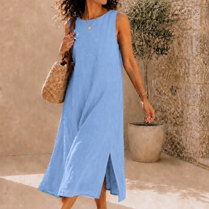 Pu&ograve; includere: Un abito midi azzurro senza maniche con scollo rotondo e spacchi laterali sull'orlo. L'abito ha una silhouette dritta e rilassata che cade sotto le ginocchia. &Egrave; abbinato a sandali in pelle marrone e a una borsa in paglia intrecciata.