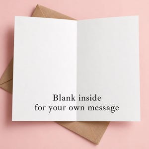 May include: A white greeting card with a fold in the center, featuring the black printed text "Blank inside for your own message" on the bottom half of the interior. The card is positioned partially inside a brown kraft paper envelope.