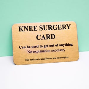 Op de afbeelding: Een rechthoekige goudkleurige kaart met afgeronde hoeken en zwarte tekst die luidt: KNEE SURGERY CARD, Can be used to get out of anything, No explanation necessary, This card can be used forever and never expires.