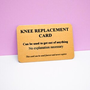 Op de afbeelding: Een rechthoekige goudkleurige kaart met afgeronde hoeken en zwarte tekst die luidt: KNEE REPLACEMENT CARD, Can be used to get out of anything, No explanation necessary, This card can be used forever and never expires.