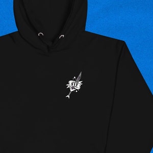 May include: Black hooded sweatshirt with a white graphic of a sword piercing a heart with the text "SIT" inside the heart.