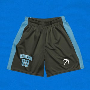 Puede incluir: Pantalones cortos deportivos negros con paneles laterales azules. Los pantalones cortos tienen un logotipo blanco en la pierna derecha y el texto "MUNDING 99" en la pierna izquierda.