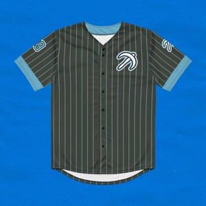 Puede incluir: Una camiseta de béisbol a rayas blancas y negras con cuello y mangas azules. La camiseta tiene un logotipo de pájaro azul en la parte delantera y el número 8 en la manga izquierda.