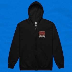 Puede incluir: Sudadera negra con cremallera, capucha y bolsillos delanteros. La sudadera presenta un gráfico llameante con la palabra "CERBERUS" en una fuente estilizada. La cremallera es plateada, sobre un fondo azul liso.