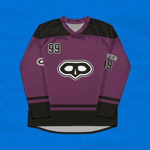 May include: A purple hockey jersey with black accents, featuring the number 99 on the front and sleeve. The jersey has a V-neck and a stylized skull logo on the chest. The word "EVING" is printed on the sleeve.
