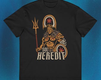Pode incluir: Uma t-shirt preta de manga curta com uma estampa gráfica de uma figura de guerreiro dourado segurando um tridente e um escudo. A figura usa um capacete e uma armadura com acabamento em pele. Abaixo, o texto SOL HEREDIT está em negrito.