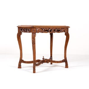 May include: An antique wooden side table with a rectangular top and ornate carved detailing. The table has curved legs and decorative carvings, finished in a rich brown colour. The table measures approximately 61 cm long, 46 cm wide, and 71 cm tall.