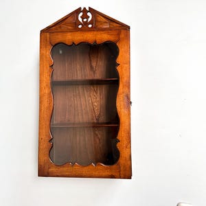 Antieke mahonie en eiken wandkast met glazen deur en decoratief embleem, jaren 1880