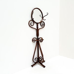 Può includere: Un attaccapanni vintage in metallo marrone con specchio ovale, ganci appendiabiti e portasciugamani. Il supporto decorativo presenta volute ornate e una base a treppiede, ideale per ingressi o camere da letto.