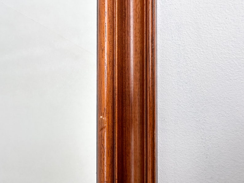 May include: Close-up of a wooden frame with a dark brown finish. The frame has a raised, decorative edge.