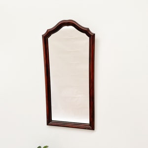 May include: A dark wood framed mirror with a beveled edge and an arched top.