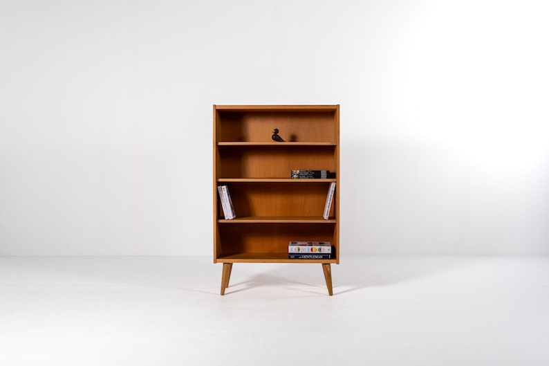 Puede incluir: Una estanter&iacute;a de madera de estilo moderno de mediados de siglo con cuatro estantes. La estanter&iacute;a es de color marr&oacute;n claro y tiene un dise&ntilde;o minimalista. Contiene libros y objetos decorativos. La estanter&iacute;a mide 122 cm de alto.