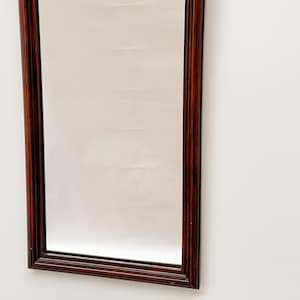 May include: A rectangular mirror with a dark wood frame. The frame has a simple, traditional design.
