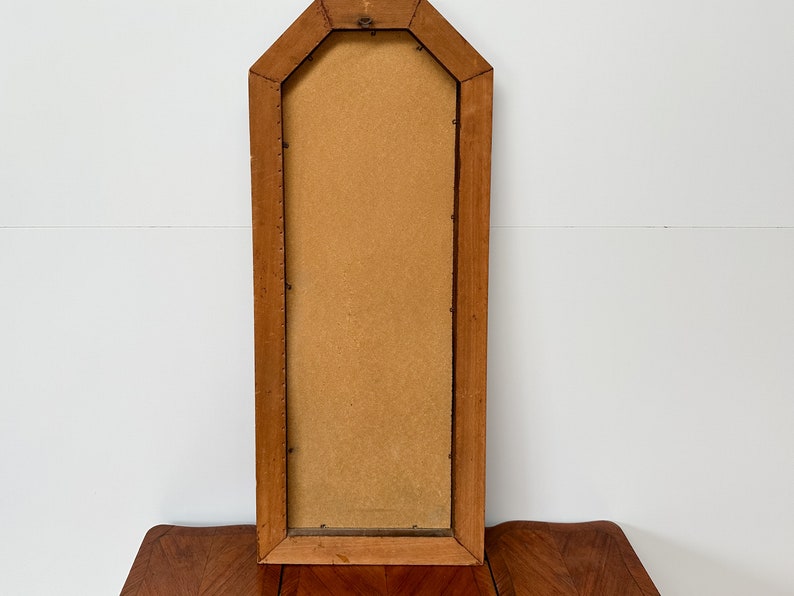 May include: A tall, rectangular wooden picture frame with a beveled edge and a light brown finish. The frame is empty and has a slightly distressed look.
