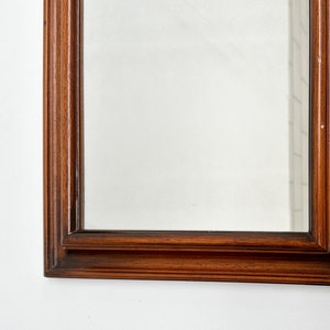 May include: A rectangular mirror with a dark wood frame. The frame has a simple, elegant design with multiple layers of molding.