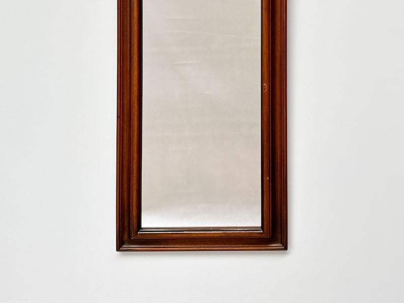 May include: A tall, rectangular mirror with a dark wood frame. The frame has a simple, traditional design.