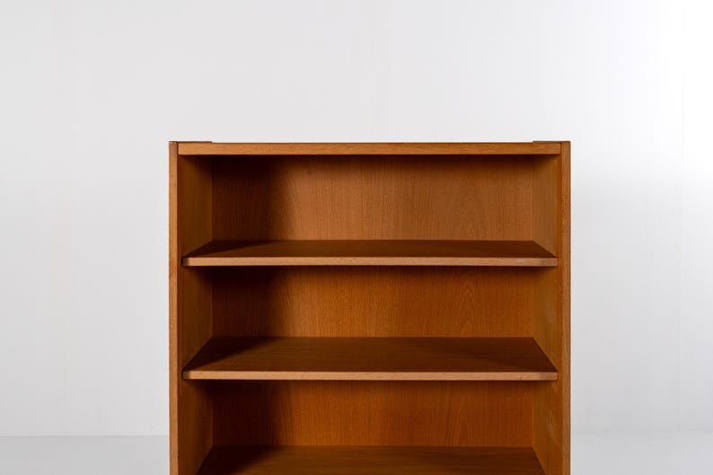 Puede incluir: Una estanter&iacute;a de madera con tres estantes. La estanter&iacute;a es de madera de color marr&oacute;n claro y tiene un dise&ntilde;o simple y rectangular. Los estantes est&aacute;n espaciados uniformemente y parecen estar vac&iacute;os. El fondo es una pared blanca lisa.