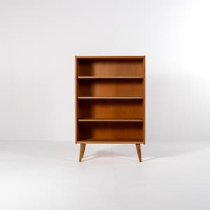 Puede incluir: Una estanter&iacute;a moderna de mediados de siglo con cuatro estantes. La estanter&iacute;a de madera es de color marr&oacute;n c&aacute;lido y se apoya en cuatro patas anguladas. Los estantes est&aacute;n abiertos y listos para el almacenamiento. La estanter&iacute;a mide aproximadamente 152 cm de altura.
