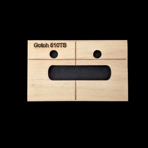 May include: A wooden template with the text "Gotoh 510TS" printed on it. The template has two circular cutouts and a rectangular cutout.