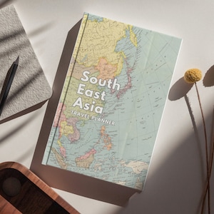 May include: A travel planner with a vintage map of Southeast Asia on the cover. The cover is white with blue, red, and yellow accents. The title "South East Asia Travel Planner" is printed in white on the cover.
