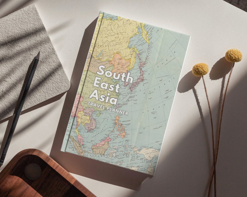 May include: A travel planner with a vintage map of Southeast Asia on the cover. The cover is white with blue, red, and yellow accents. The title "South East Asia Travel Planner" is printed in white on the cover.